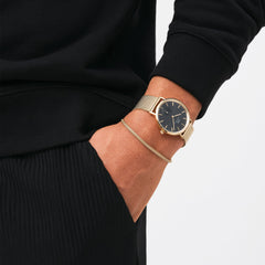 A person wearing the Tide Mesh Bracelet Evergold 2.8 alongside a gold mesh watch, showing the bracelet’s slim gold mesh design and elegant, understated style.