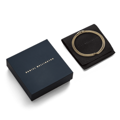 Tide Mesh Necklace Gold 2.8 displayed in its signature Daniel Wellington packaging, featuring a gold mesh chain neatly arranged on a black pouch beside a navy gift box.