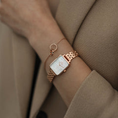 Quadro Lumine 5 Link Melrose White MoP Rose Gold women’s watch with a rectangular rose gold case and white mother of pearl dial, styled on the wrist with a matching rose gold bracelet and a beige coat.