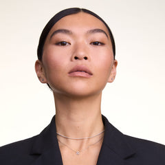 A woman wears the Charms Snake Necklace S925 Sterling Silver as a sleek choker layered above a delicate charm necklace, styled with a dark blazer for a modern, elegant look.
