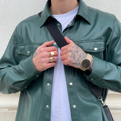 Man wearing the Classic Mesh Onyx Gold wristwatch with a black dial and gold mesh strap, styled with a green leather jacket and white shirt.