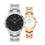 Two Daniel Wellington watches from the Iconic Link White Rose Gold & Black Silver set, featuring one with a silver link strap and black dial, and the other with a rose gold link strap and white face, both showcasing minimalist design and refined detailing.