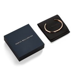 Classic Lumine Bracelet Rose Gold 55mm displayed on a black Daniel Wellington pouch beside its signature navy gift box, highlighting the bracelet’s polished rose gold finish and cubic zirconia crystal detailing.