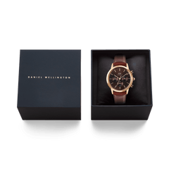 Iconic Chronograph St Mawes Amber RG men’s watch with a rose gold case and brown leather strap, presented in an open Daniel Wellington gift box alongside the branded lid.