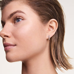 A woman wears a petite silver geometric hoop earring with a distinctive three-link design, showcasing its polished finish and contemporary style.
