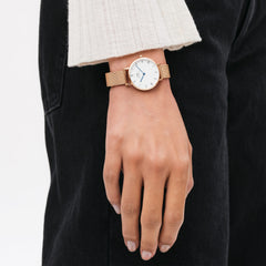 Woman wearing Petite Roman Numerals Melrose watch with rose gold mesh strap and white Roman numeral dial by Daniel Wellington.