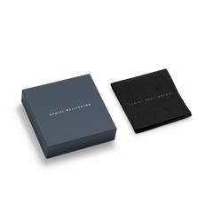 Elegant Daniel Wellington packaging for the Charms Chain Bracelet RG, featuring a navy blue gift box and a black protective pouch, both with gold branding.