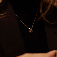 The Elevation Necklace Gold with a geometric pendant is worn over a black top, showcasing its polished finish and elegant, minimal style.