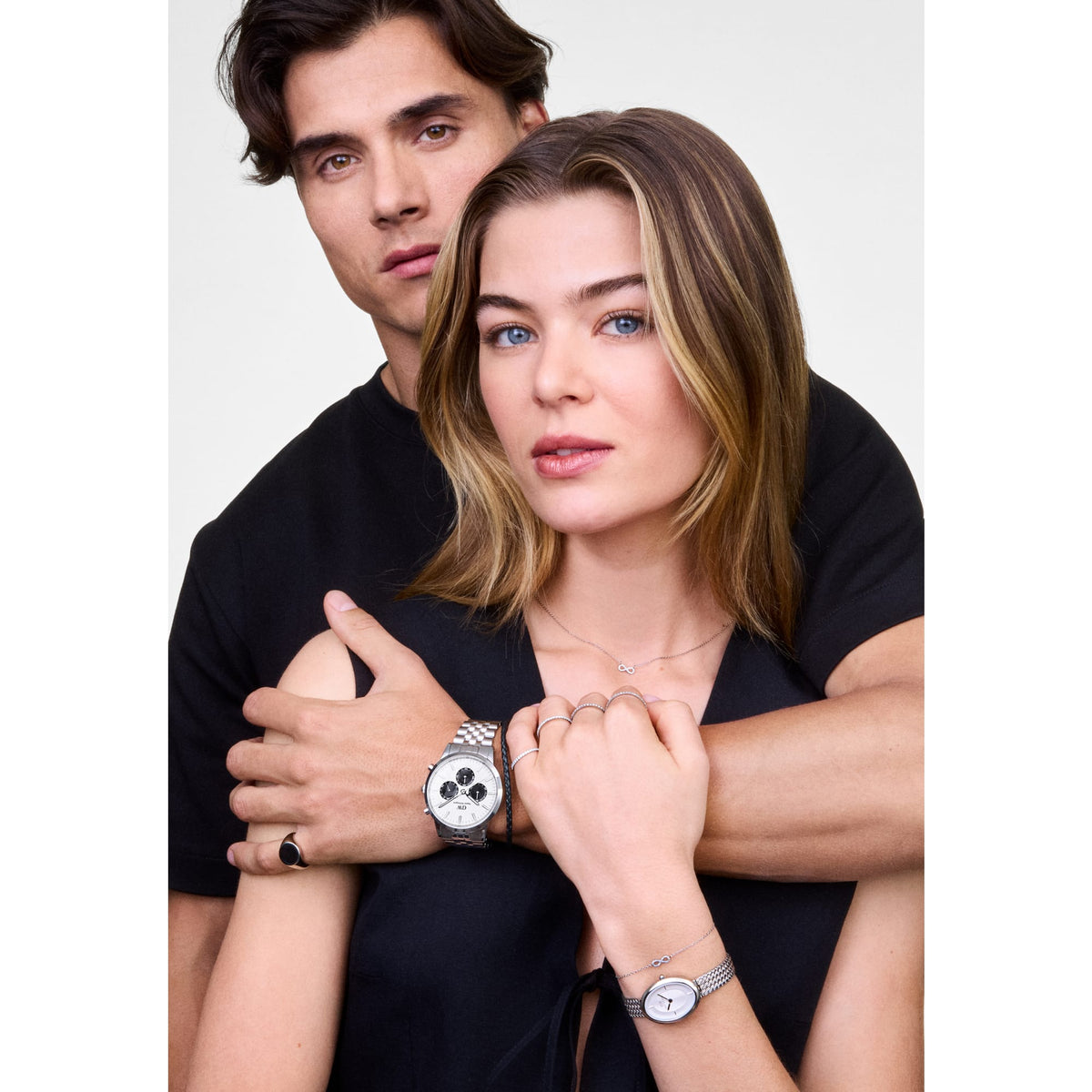 A woman wearing the Mirelle Infinity Bracelet Silver on her wrist, styled with a matching silver watch and rings, showing the delicate chain and sparkling infinity symbol set with cubic zirconia crystals.