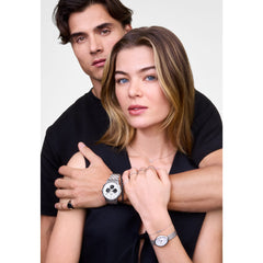 A woman wearing the Mirelle Infinity Bracelet Silver on her wrist, styled with a matching silver watch and rings, showing the delicate chain and sparkling infinity symbol set with cubic zirconia crystals.