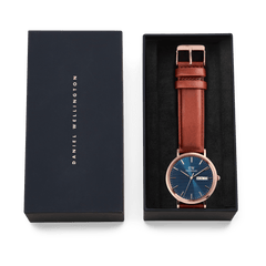 Classic Day Display St Mawes Rose Gold Arctic watch with a blue dial and brown leather strap, presented in an elegant Daniel Wellington gift box.