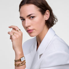 Woman wearing the Classic Aura Ring Gold on her hand, styled with other gold rings, a gold watch, and gold bangles, paired with a crisp white blazer for an elegant and modern look.
