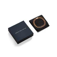 Chunky Chain Bracelet Rose Gold displayed on a black cushion beside a sleek Daniel Wellington gift box, highlighting its polished links and elegant presentation.