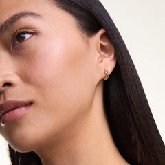 A woman wears a single 3-Link rose gold earring with a geometric, linked design, showcasing its elegant and modern style against her skin.