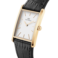 Elegant Daniel Wellington watch featuring a rectangular gold case, minimalist white dial with gold markers, and a black crocodile-embossed leather strap. The softly curved profile and refined detailing create a sophisticated, timeless look.