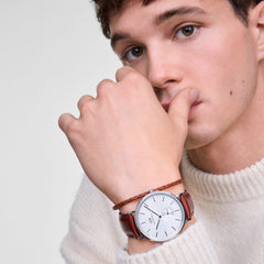 A man wearing the Classic Multi-Eye St Mawes Off-white Sunray Silver watch with a brown leather strap and silver case, styled alongside a braided bracelet and a cream knit jumper for a refined, casual look.