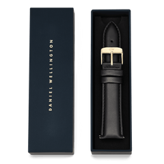 Tapered Sheffield Strap Gold presented in a navy Daniel Wellington gift box, showcasing the black leather strap with a polished gold buckle and refined stitching.