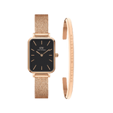 Rectangular rose gold watch with a black dial and matching mesh strap, paired with a slim rose gold bracelet engraved with the Daniel Wellington logo. Both pieces feature a minimalist, elegant design ideal for sophisticated styling.