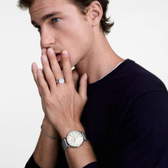 Man wearing the Classic Day Display Sterling Champagne watch, featuring a champagne dial with day and date display, silver mesh strap, and minimalist design, styled with a dark jumper for a refined everyday look.