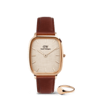 Rose gold Daniel Wellington square-faced watch with a brown leather strap, paired with a minimalist rose gold signet ring, both displayed against a plain background.