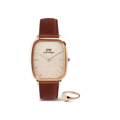 Rose gold Daniel Wellington square-faced watch with a brown leather strap, paired with a minimalist rose gold signet ring, both displayed against a plain background.