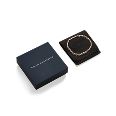 3-Link Bracelet Gold displayed on a black pouch next to an elegant Daniel Wellington gift box, highlighting its suitability for gifting.