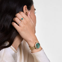 Woman wearing Audrey Ring Malachite Gold with green malachite centre and cubic zirconia halo, styled with gold watch.