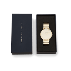 Classic Piano Link Gold Unitone watch with a brushed gold dial and piano link bracelet, elegantly presented in a black Daniel Wellington gift box.