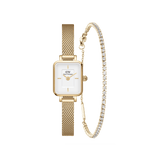 Gold Daniel Wellington Quadro Mini watch with a rectangular white dial and mesh strap, paired with a slender gold tennis bracelet featuring a row of sparkling stones.