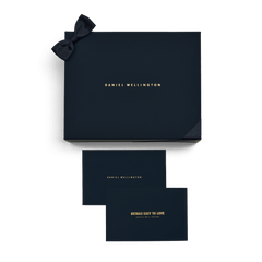 Navy blue Premium Gift Box with a ribbon bow and gold Daniel Wellington branding, shown with two matching cards, ideal for presenting jewellery, watches, or special gifts.