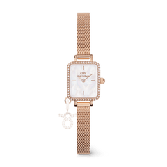 Elegant women's rose gold watch with a rectangular crystal-set bezel, white mother of pearl dial, and a fine mesh strap, featuring a sparkling zodiac charm attached to the band.