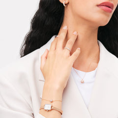 Woman wearing the Pavé Crystal Pendant Necklace Rose Gold, styled with matching rose gold jewellery and a white blazer for an elegant, coordinated look.