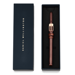 Pressed St Mawes Strap Rose Gold presented in a navy Daniel Wellington gift box, featuring a slim brown genuine leather band with a polished rose gold buckle.