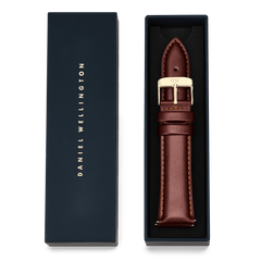 Tapered St Mawes Strap Gold presented in a navy Daniel Wellington gift box, featuring genuine brown leather with contrast stitching and a polished gold buckle for an elegant, refined finish.