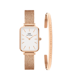 Rectangular rose gold Daniel Wellington watch with a white dial and mesh strap, paired with a matching rose gold bracelet engraved with the brand name. Both pieces feature a minimalist, elegant design crafted from high-quality steel.