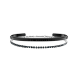 A sleek black Daniel Wellington cuff engraved with the brand name is paired with a silver tennis bracelet featuring a row of sparkling stones, displayed together to showcase their modern, elegant contrast.