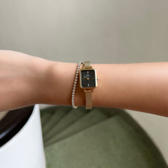 Quadro Mini Evergold Onyx gold mesh women’s watch with black dial, styled on wrist beside a delicate diamond bracelet.