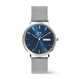 Classic men’s watch with a polished silver mesh strap, round stainless steel case, and a textured blue dial featuring day and date display. The elegant Daniel Wellington design combines timeless style with everyday practicality.
