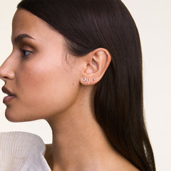 A woman wears the Crystal Moon, Crystal Bar, and Crystal Stud gold earrings together on one ear, showcasing the set’s celestial-inspired shapes and sparkling crystals in a modern, layered style.