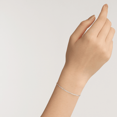 A delicate silver flat chain bracelet with a minimalist design is worn on the wrist, showcasing its slim and elegant style.