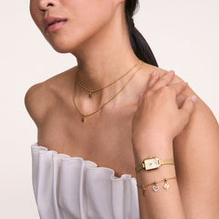 Woman wearing Quadro Mini Evergold Champagne gold mesh strap watch with champagne dial, styled with gold jewellery.