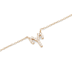 Close-up of a gold zodiac chain necklace featuring a sparkling crystal-encrusted pendant in a claw setting.