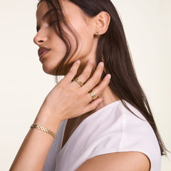 Woman wearing the 3-Link Bracelet Gold on her wrist, styled with matching gold rings and earrings for a coordinated, elegant look.