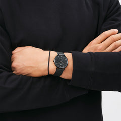 Man wearing the Classic Multi-Eye Ashfield Onyx watch with a black mesh strap and minimalist black dial, styled with a casual black jumper.