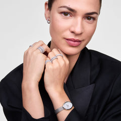 Woman wearing the Juliette Braided Mesh White Sunray Silver watch with an oval silver case and braided stainless steel mesh strap, styled with silver rings and a black blazer for a sophisticated, modern look.