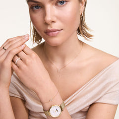 Woman wearing the Crystal Zodiac Chain Necklace Silver with a sparkling zodiac pendant, styled elegantly with a gold watch and matching jewellery.