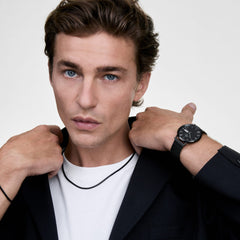 A man wearing the Tide Mesh Necklace Black 1.8, styled over a white T-shirt and black blazer, paired with a matching black mesh watch for a coordinated, modern look.