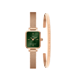 Rose gold Daniel Wellington Quadro Mini watch with a rectangular emerald green dial and matching mesh strap, paired with a slim rose gold bracelet engraved with the brand name.