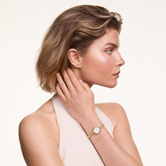 A woman wearing the Flower Stud Gold earring styled with a minimalist gold watch and bracelet, showcasing the delicate floral stud on her ear for an elegant everyday look.
