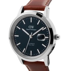 Close-up of the Iconic St Mawes Automatic Silver watch featuring an arctic blue enamel dial, polished stainless steel case, magnified date display, and a brown Italian leather strap.